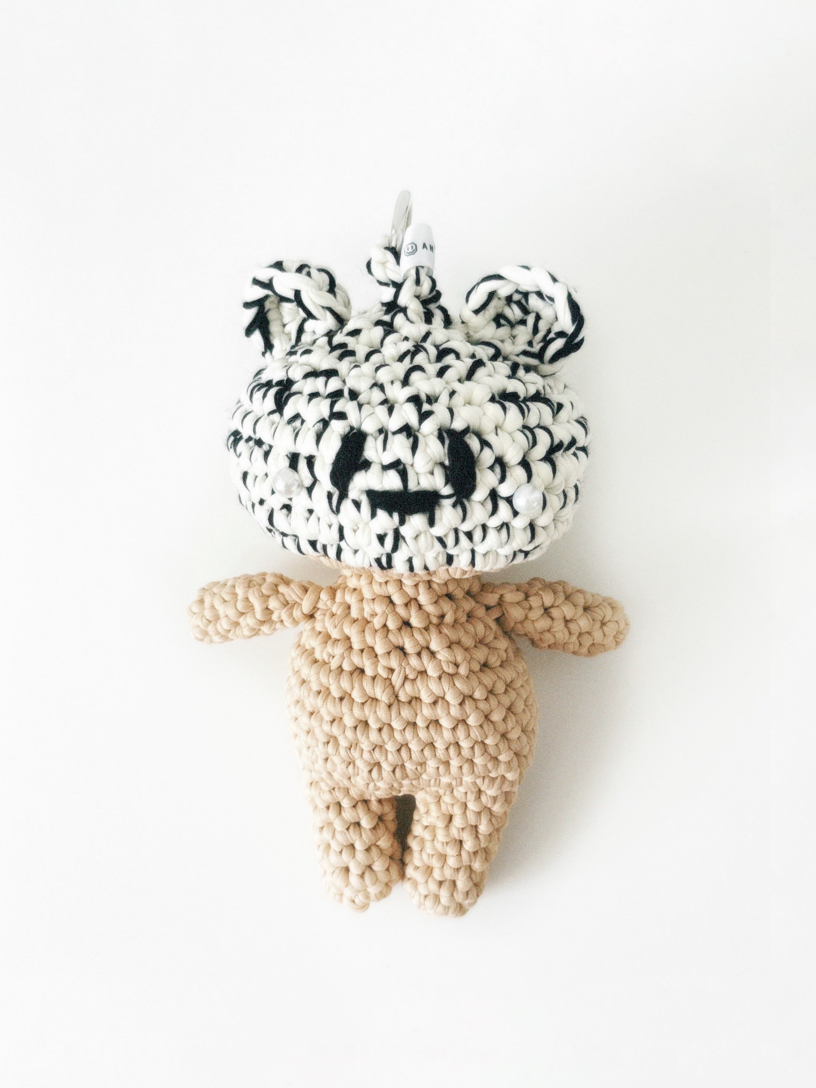 Crochet bag charm with a black and white patterned hat on a white background